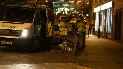 Kvinna sitter på trottoarkanten efter händelsen i Manchester och polisen finns på plats.
