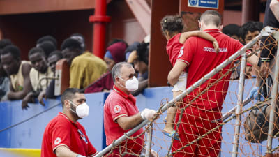 Ett barn bärs ut från en räddningsbåt i Italien med flyktingar ombord 