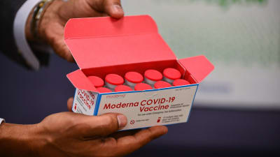 En person håller i en låda som innehåller doser av coronavaccinet av märket Moderna. På lådan står det "Moderna covid-19 vaccine".