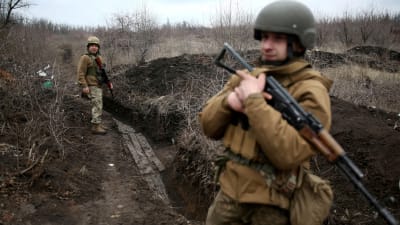 Två ukrainska soldater patrullerar längs en lerig löpgrav