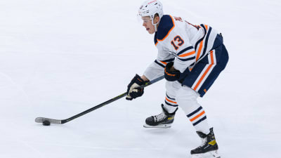 Jesse Puljujärvi för fram pucken på isen, iklädd Edmonton Oilers vita speldräkt.