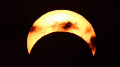 Solen bildar en gul skära mot en svart bakgrund. Några moln frmaför skäran ser röda och svarta ut. Bilden togs i Kuwait tidigt den 26 december 2019.