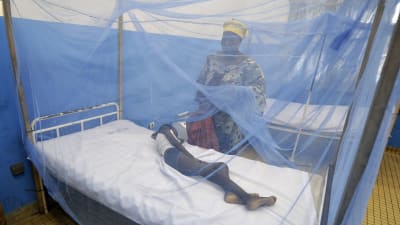 Kvinna vakar över ett barn som insjuknat i malaria