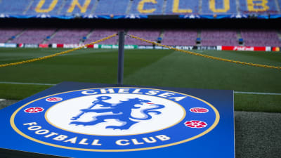 Chelsea FC:s logo med läktare i bakgrunden.