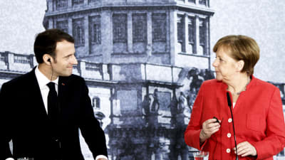 Emmanuel Macron och Angela Merkel tittar på varandra under en presskonferens i Berlin.