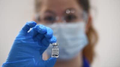 En hälsovårdare i London håller upp Pfizer/Biontechs coronavirusvaccin.