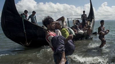 Arkivbild på en bangladeshisk man som hjälper flyende rohingyer att ta sig i land på bangladeshisk mark vid floden Naf den 30 september 2017.