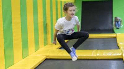 En flicka hoppar på en trampolin i en aktivitetshall.