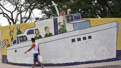 En man passerar ett mosaikarbete i Havanna som visar Che Guevara, Raúl och Fidel Castro. Lördagen 16.4.2016