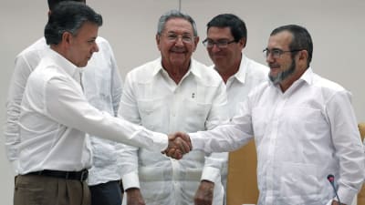 Colombias president santos och Farc-ledaren Londono skkar hand efter i överenskommelse i Kuba.