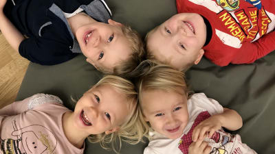 Fyra glada barn ligger på en matta.