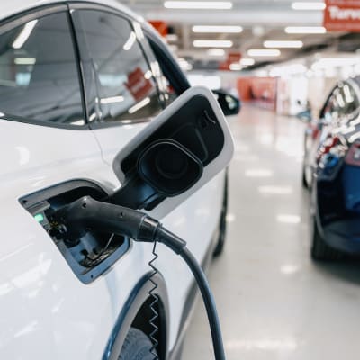 Sähköauto latauksessa autoliikkeessä.