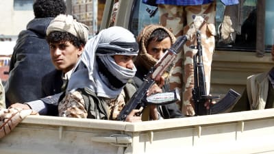 Rebeller i Jemen sitter på ett bilflak med stormgevär i famnen.