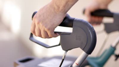 En hand håller i en rollator.