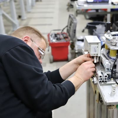Automaatiasentaja Jimi Valo asentamassa tarttujaa, joka kiinnittyy robottiin Orferin tehtaalla Orimattilassa.
