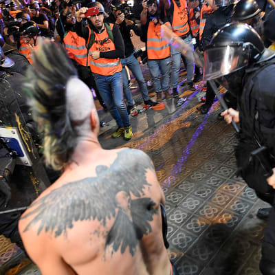 Kravallpolis angriper en demonstrant under natten kravaller i Barcelona