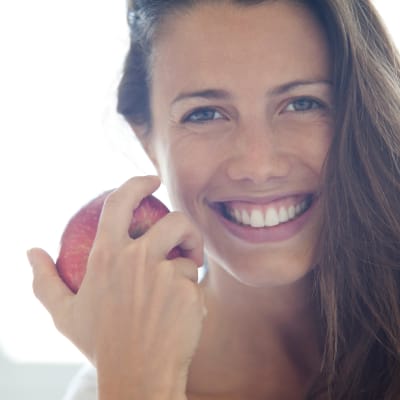 Leende kvinna håller ett äpple.