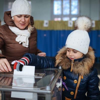Kvinna med dotter vid vallokal i Ukraina