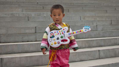 En liten pojke med leksaksgitarr i Pyongyang i Nordkorea