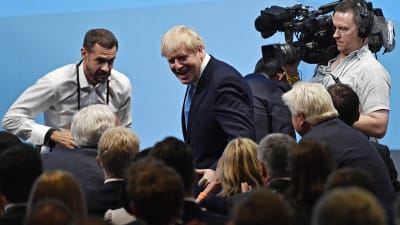 Boris Johnson omringad av kameror.