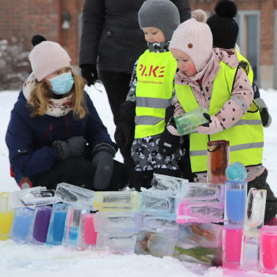 Lapset rakentavat jääpalikoista taideteosta talvisella pihalla
