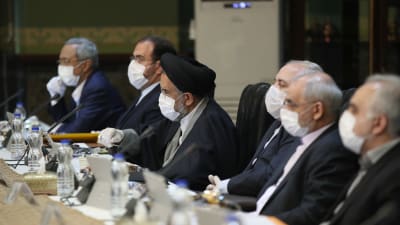 Den iranska regeringen sammanträder. Alla ministrar är iförda ansiktsmasker