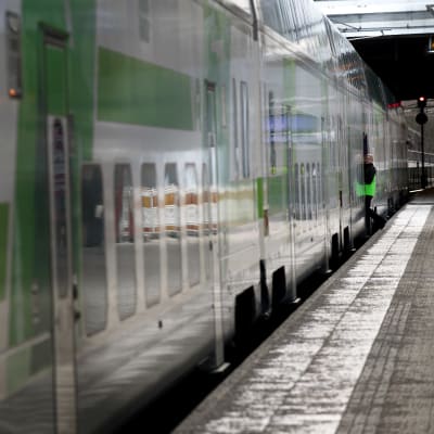 En konduktör syns vid dörren till ett tåg vid Helsingfors centralstation.