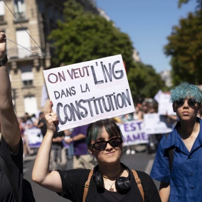 Tre personer under en demonstration för aborträttigheter i Paris.