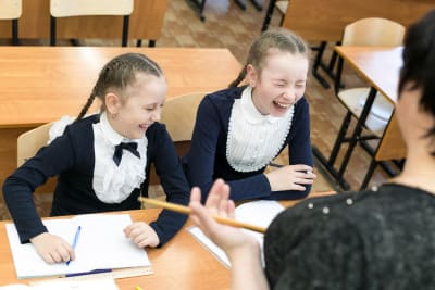 Kaksi koulutyttöä nauraa luokassa.