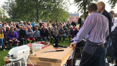 Michael Björklund och Matias Jungar kockar inför en stor publik som sitter i en park.