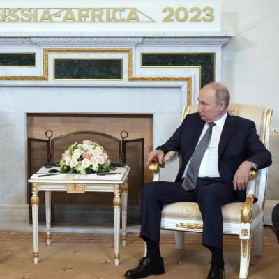 Dilma Rousseff ja Vladimir Putin istuvat koristeelllisilla tuoleilla takan edustalla, jonka yllä lukee Russia-Africa 2023.