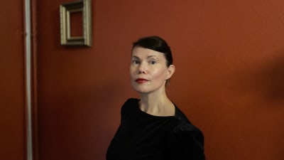 En mörkhårig kvinna framför en röd vägg