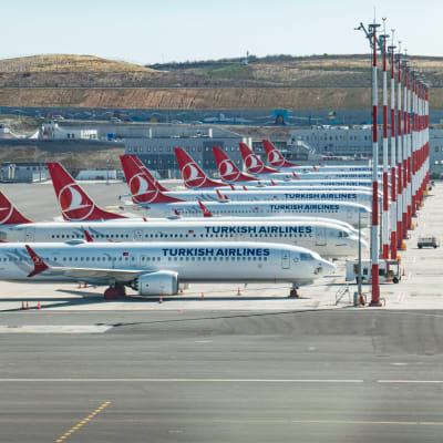 Vita flygplan med röda detaljer står på rad på en enorm flygplats.