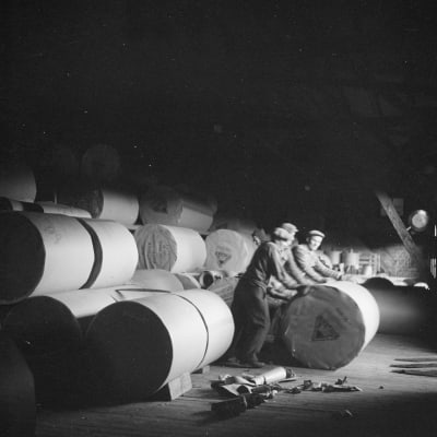Arbetare hanterar pappersrullor på en pappersfabrik 1947. Svartvitt foto ur Museiverkets samlingar. 