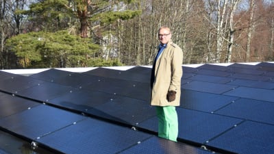 Denis Strandell står på ett tak fyllt med solpaneler.