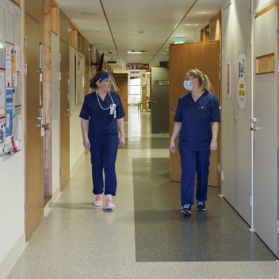 Två personer i ÅUCS personal i en sjukhuskorridor. 