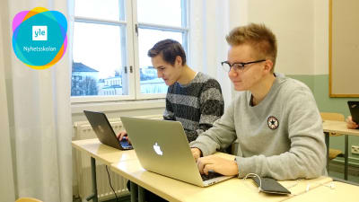 Två skolelever jobbar vid sina datorer under en lektion.