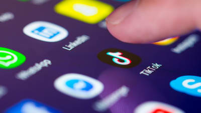 Ett finger syns över TikToks ikon på en smarttelefon.