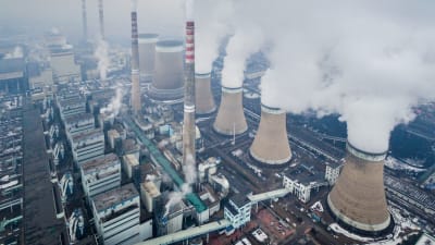 Flera fabriksbyggnader, skorstenar och nedkylningstorn vid kinesiskt kolkraftverk fotograferade uppifrån.  