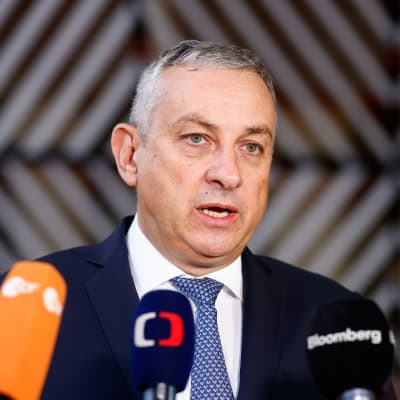 På bilden syns Tjeckiens industri- och handelsminister Jozef Sikela. Han är en gråhårig man som här möter pressen inför ett möte. Han är iklädd kostym och flera mediers mikrofoner är placerade framför honom.
