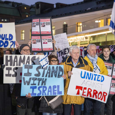Demonstranter håller plakat med slagord mot Hamas och till stöd för Israel. 