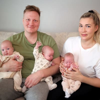 Jesse Paananen ja Marianne Nukarinen istuvat sohvalla sylissään kaikki kolme vauvaa.