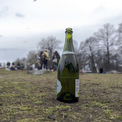 En flaska skumvin i Brunnsparken den 1 maj 2023. I bakgrunden grupper av människor.