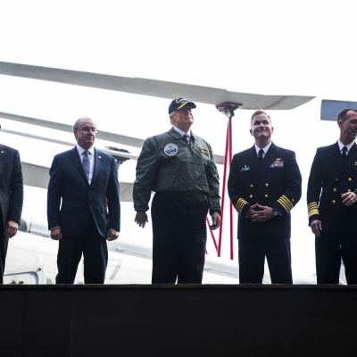 Donald Trump iklädd flygarjacka och skärmmössa på hangarfartyget Gerald R. Ford.