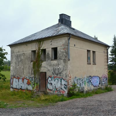 Ett gammalt kvadratformat hus med graffiti på väggarna.