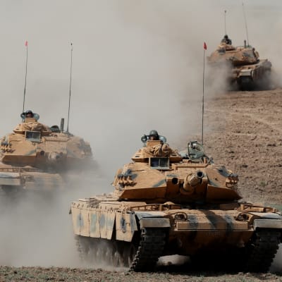 Tre turkiska stridsvagnar kör i ett löst led mot kameran. 