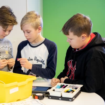 Lietsalan koulun viidesluokkalaiset Niclas Noko, Lauri Luoto ja Konsta Evesti kasaavat koodattavaa robottia.