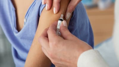 En flicka vaccineras med en spruta i armen.