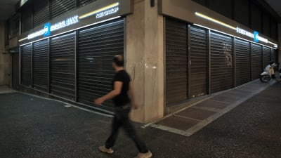 En man passerar ett stängt bankkontor i Aten den 28 juni 2015.