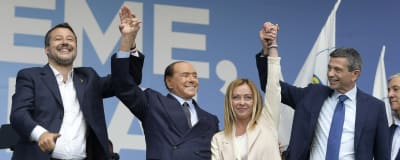 Fyra italienska politiker står på scen och håller i varandras händer och ler.